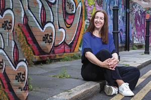 Ines Respini Jones sitting on a pavement in front of a graffitied wall