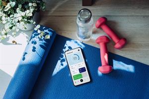 Workout equipment on floor with wellness app shown on phone