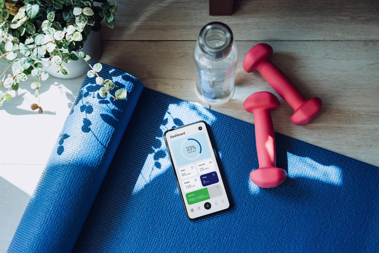 Workout equipment on floor with wellness app shown on phone