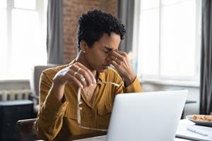 a female employee looking tired and in pain sitting at a desk