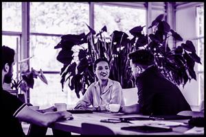 People sat around a table with a big plant in the background