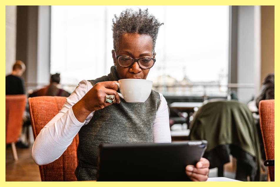 Woman drinking coffee while holding a tablet