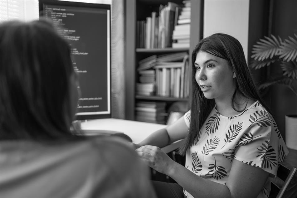Two people sat talking in front of a screen