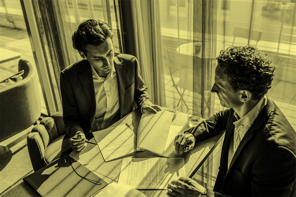 Two people sat at a table looking at documents