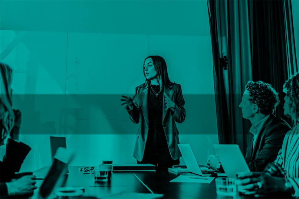 Person talking and stood in front of a table with people sat around it