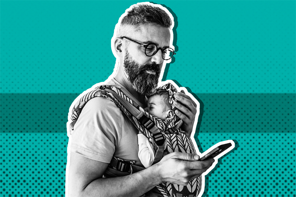 Dad holding baby while looking at phone