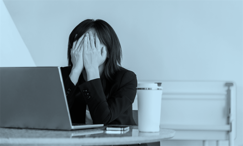Person sat in front of a laptop with hands over their face