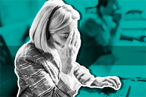 Woman sat at a desk with hand on their face