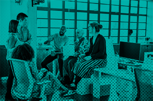 Group of people sat on desk and chairs in an office