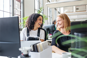 Two casually dressed female colleagues smiling at each other