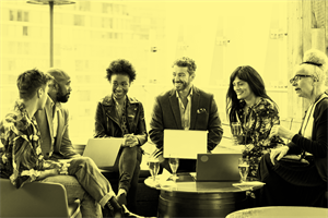 Group of people sat down with laptops, talking