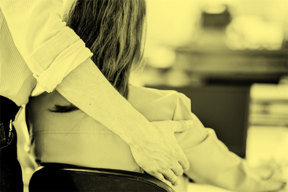 Close up of someone with their arm around someone sitting down