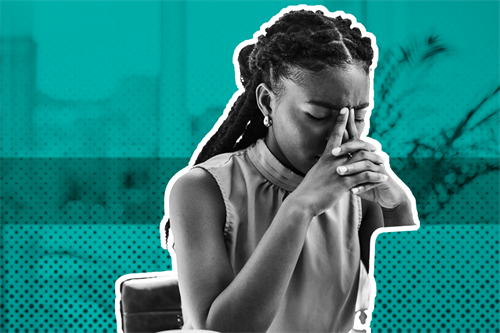 Woman at a desk with eyes closed and hands on face