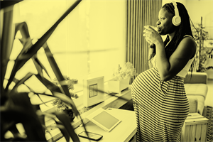 Pregnant woman standing drinking next to a window