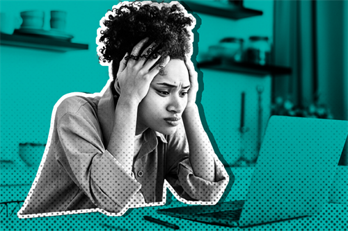 Woman sat at a laptop with hands on her head