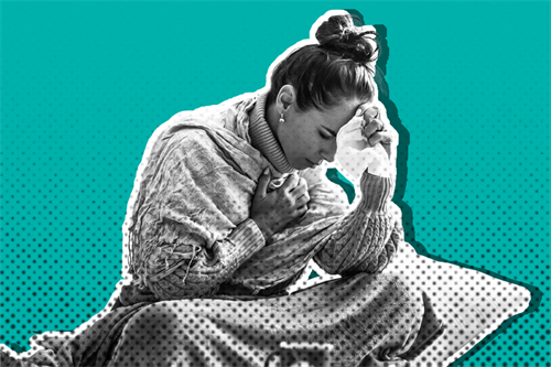 Woman sat clutching her chest and holding a tissue