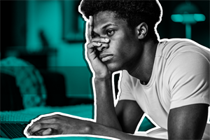 Man lying on a bed with a laptop and hand on his face