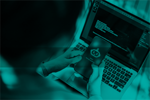 Person holding a phone with a chatbot on it in front of a laptop