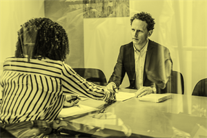 Two people sat at a table in an office meeting room