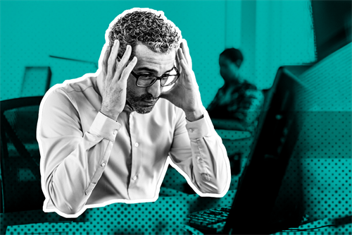 Man sat at desk with hands on his head