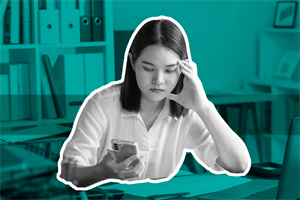 Person sat at a desk looking at a mobile phone