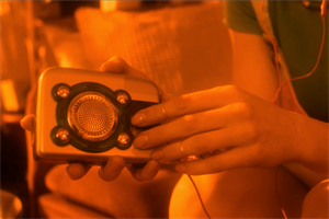 A woman's hand holding a Walkman with an orange filter